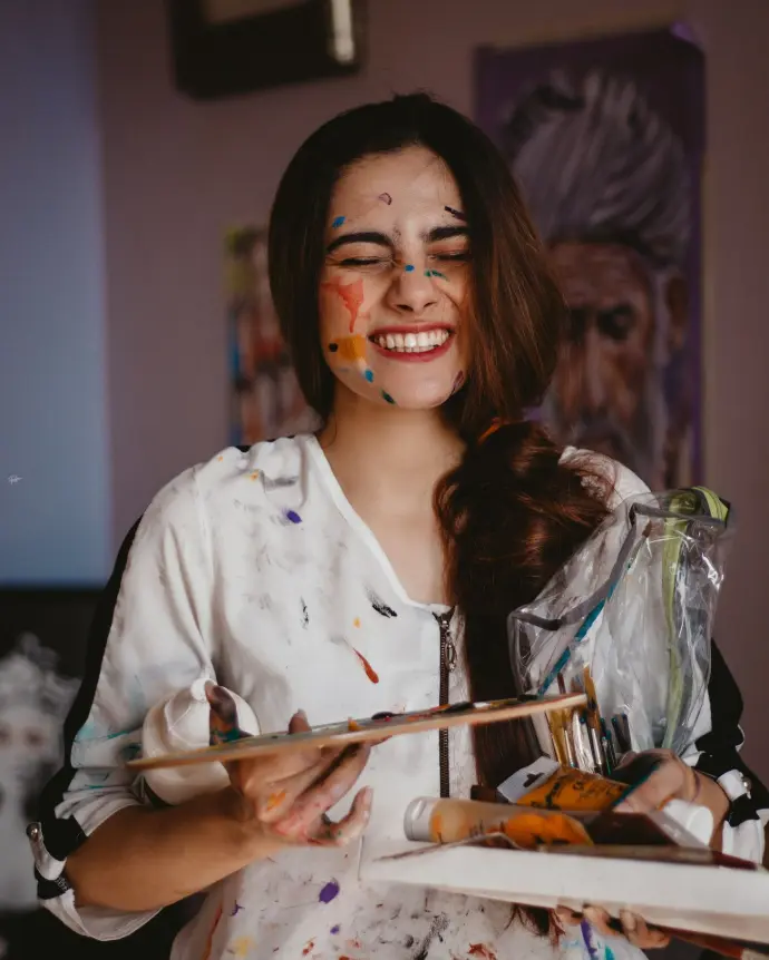 a woman with face paint holding a paintbrush and palette
